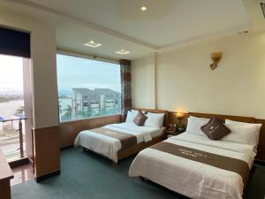 een hotelkamer met 2 bedden en een groot raam bij Phuong Anh 3 Hotel in Hai Phong