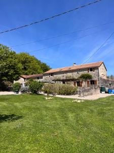 an old stone house with a green yard at Le Plantier 1 in Beaulieu-sur-Sonnette