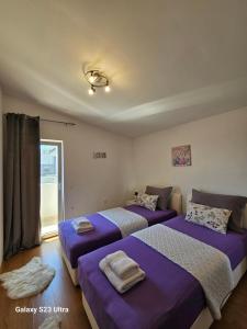 two beds in a room with purple sheets at Apartmani Dianna in Kaštela