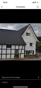 a picture of a white house with a black roof at Ferienhaus Wietsche in Burscheid