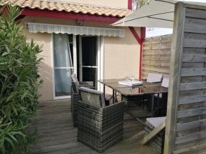 eine Holzterrasse mit einem Tisch und einem Sonnenschirm in der Unterkunft Villa Atlantis 4-8 pers super équipée proche océan in Soustons