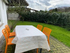 a table with four orange chairs and a table with a white table cloth at Ferienhaus Wietsche in Burscheid