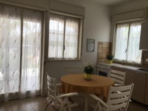 a kitchen with a table and chairs and windows at Villa Acacie Capì in Villaggio San Leonardo