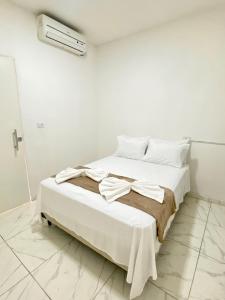 a white bedroom with a bed with white sheets and pillows at Pousada Velho Brito in Piranhas