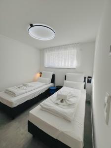 een witte kamer met 2 bedden en een licht bij Xzllenz - 4 Schlafzimmer, Zentral, Parken, U-Bahn, 2 Bäder, 4 Smart-TV, optional Einzelbett in Neurenberg