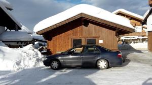 une voiture garée devant une maison recouverte de neige dans l'établissement Ferienwohnung für 4 Personen ca 45 qm in Ehrwald, Tirol Gaistal, à Ehrwald