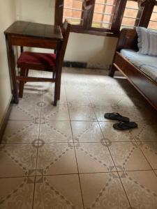 Pokój z podłogą wyłożoną kafelkami, stołem i sandałami w obiekcie Nzimano Hostel w Kigomie