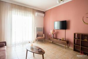 Una sala de estar con un sofá y un televisor en la pared. en AXDHOME venizelou project by homebrain, en Alexandroupoli