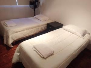 2 bedden in een hotelkamer met witte lakens bij Departamento Colon in Mendoza