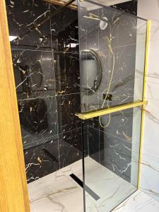 a glass shower with a black marble wall at LUX HOUSE Roztocze Sauna i Bania z hydromasażem in Krasnobród