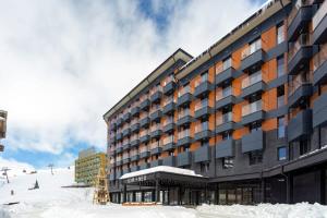 un gran edificio con nieve frente a una pista de esquí en Cozy Studio Ski In Out Apartment In New Gudauri en Gudauri