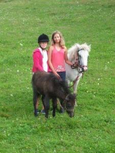dos chicas de pie junto a un caballo y un poni en Ferienwohnung für 4 Personen ca 50 qm in Bleiburg, Kärnten Unterkärnten, en Bleiburg