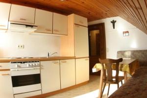 una cucina con armadi bianchi, tavolo e sedia di Ferienwohnung für 4 Personen ca 50 qm in Bleiburg, Kärnten Unterkärnten a Bleiburg