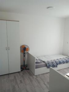 een witte slaapkamer met een bed en een ventilator bij Apartment Hristef in Ljubaništa