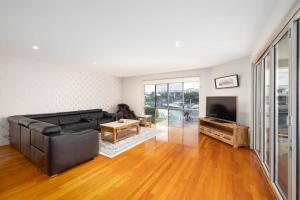 a living room with a black leather couch and a television at 3BR Serene Waterfront Retreat with pool & dock in Gold Coast