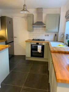 a kitchen with a sink and a stove top oven at Spacious Stylish House Close to M4 Private Parking in Magor