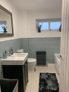 ein Badezimmer mit einem Waschbecken, einem WC und einem Spiegel in der Unterkunft Spacious Stylish House Close to M4 Private Parking in Magor