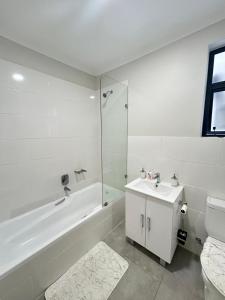 bagno bianco con vasca, lavandino e servizi igienici di Feels Like Home Condo Victoria Falls a Victoria Falls