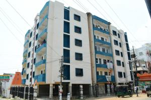 a white building with blue windows on a street at Rivasa homes in Deoghar