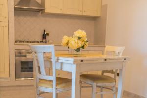 ロコロトンドにあるVilla Caramiaのキッチン(テーブル、椅子、黄色い花の花瓶付)