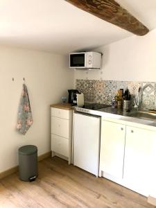 uma cozinha com armários brancos e um micro-ondas em Logement neuf et climatisé, au coeur du village em Saint-Didier