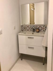 uma casa de banho com um lavatório branco e um espelho. em Logement neuf et climatisé, au coeur du village em Saint-Didier