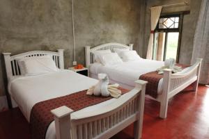 two beds in a bedroom with two stuffed animals on them at Phu-Anna Eco House in Hot