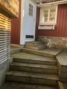 un porche delantero de una casa con escaleras y una puerta en Lillstuga Badholmen, en Fjällbacka