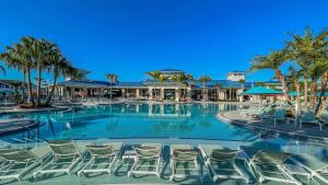 a large swimming pool with chairs and palm trees at Charming Retreat in Orlando