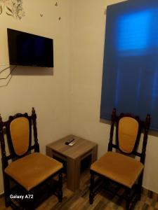 Pokój z dwoma krzesłami, stołem i telewizorem w obiekcie Cottage Heights w Nikozji