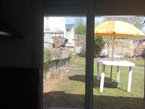 a table with a yellow umbrella in a yard at Maison avec jardin in Caen