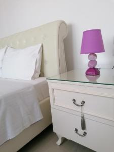 une lampe violette sur une commode à côté d'un lit dans l'établissement Nikitihouse Apartments 2, à Nikiti
