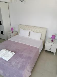 a white bedroom with a large bed with two lamps at Nikitihouse Apartments 2 in Nikiti