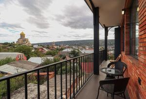 - un balcon avec deux chaises et une table dans un bâtiment dans l'établissement Modern Apartment Overlooking Tbilisi, à Tbilissi