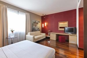 Habitación de hotel con cama y escritorio con TV. en Inverigo Hotel, en Inverigo