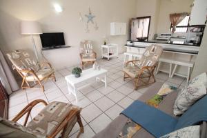 een woonkamer met een bank en stoelen en een keuken bij Natspat 9 in Uvongo Beach