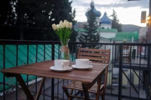 einem Holztisch mit zwei Tassen und einer Vase Blumen in der Unterkunft Comfy 3 Apartment house for 9 people in Tbilisi City