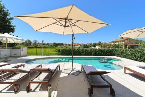 une terrasse avec des chaises et un parasol ainsi qu'une piscine dans l'établissement Ferienwohnung für 4 Personen ca 40 qm in Fažana-Surida, Istrien Istrische Riviera - b55461, à Valbandon