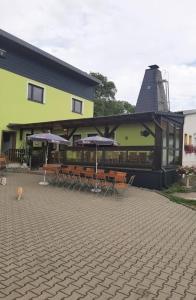 a building with tables and chairs and umbrellas at Ferienhof im grünen Herzen in Dittersdorf