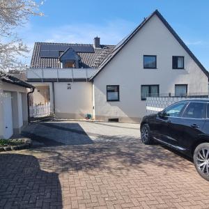 ein schwarzes Auto, das vor einem weißen Haus geparkt ist in der Unterkunft 25 Schützenstraße in Diekholzen