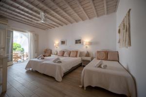 a white bedroom with two beds and a couch at TWINS-TRISA APARTMENTS in Ornos