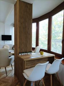 a living room with white chairs and a wooden table at Apartman Rajska Banja in Vrnjačka Banja