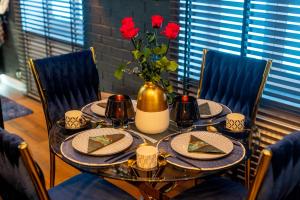 einen Tisch mit Teller mit Lebensmitteln und eine Vase mit roten Blumen in der Unterkunft Apartament Wonderland by Managerent in Słupsk