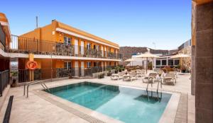a pool in front of a building with a hotel at Granada I Apartment- Patalavaca in Patalavaca
