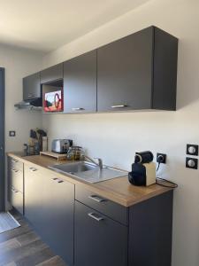 a kitchen with black cabinets and a sink at Superbe Studio meublé idéal pour couple ZEN avec SPA in Sanguinet