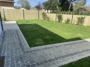 a garden with a brick walkway and a lawn at Superbe Studio meublé idéal pour couple ZEN avec SPA in Sanguinet