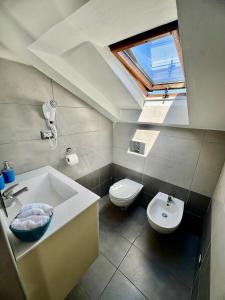 bagno con lavandino, servizi igienici e lucernario. di Sky Loft ad Alba