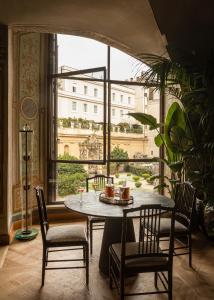 une table et des chaises dans une chambre avec une grande fenêtre dans l'établissement Palazzo Shedir - The Leading Hotels of the World, à Rome