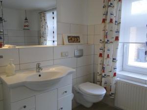 uma casa de banho com um lavatório, um WC e uma janela. em Captains Corner, 999 Schritte bis zur Ostsee em Wustrow