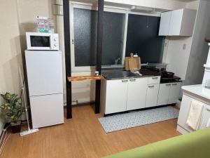 La cuisine est équipée d'un réfrigérateur blanc et d'un four micro-ondes. dans l'établissement Monster lodge 札幌, à Sapporo